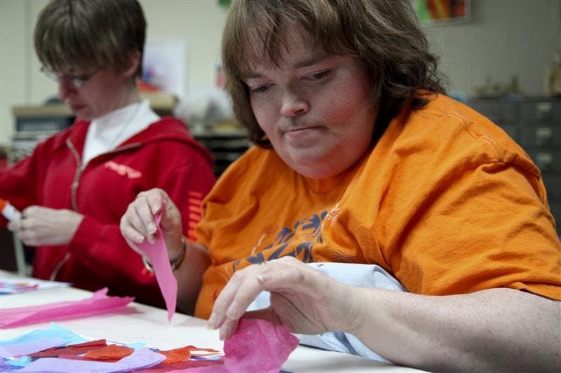 Kelly Tate and Denise Hillenburg arrange colorful paper in Andy Warhol style April 1 at Stone Belt in Bloomington. Art instructor and facilitator Karen Holtzclaw helped them select colors.