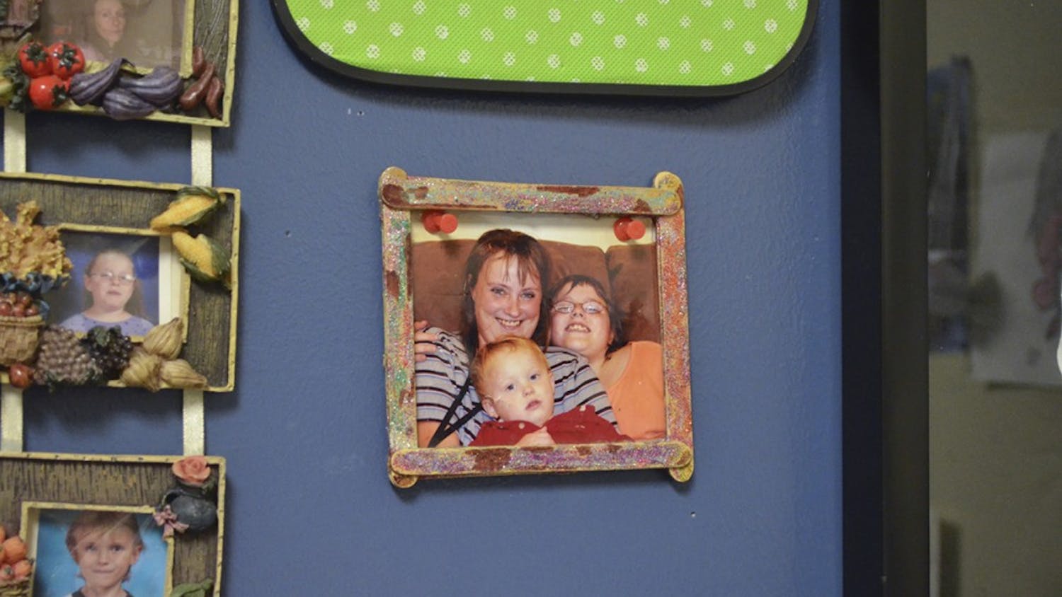 A photo of Nicole Allen, her mother and her brother hangs above her desk. The photo is a reminder of the promise she made to her mother before she died.&nbsp;