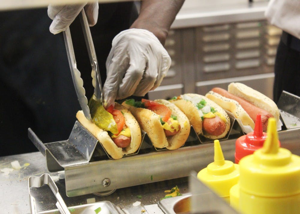 <p>Workers at Portillo&#x27;s carefully place the toppings on hot dogs to fulfill orders.</p>