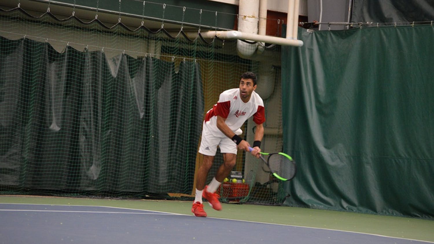 Junior Raheel Manji dives for the ball during the Hoosiers' tennis match against Louisville on Feb. 8. Manji won both his singles and doubles match Thursday, but IU lost in the first round of the Big Ten Tournament to Minnesota. 