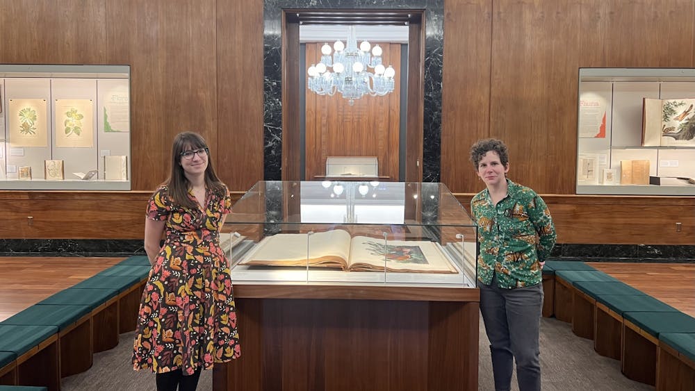 Erin Chiparo (left) and Isabel Huber Planton (right) stand next to &quot;Audubon&#x27;s Birds of America&quot; on Feb. 2, 2023, at Lilly Library. Lilly Library will host “Flora + Fauna: A Bounty of Beast and Botanicals,” which will feature curated pieces that explore the connection between humanity and nature.