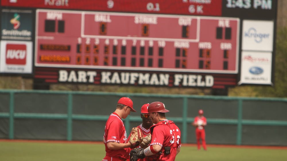 Three IU baseball team members huddle on the field April 24, 2022, at Bart Kaufman Field.  Indiana will play Iowa in a three-game series starting Thursday. 