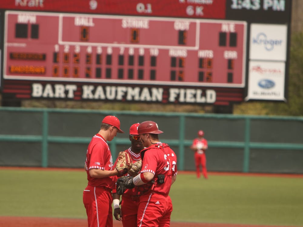 Three IU baseball team members huddle on the field April 24, 2022, at Bart Kaufman Field.  Indiana will play Iowa in a three-game series starting Thursday. 