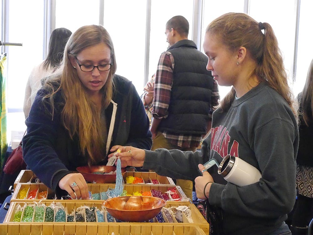 Chelsey Mountain and Jessica Mountain share experiences of bead work with each other during the 5th Annual Traditional Powwow on Saturday afternoon in Alumni Hall. 