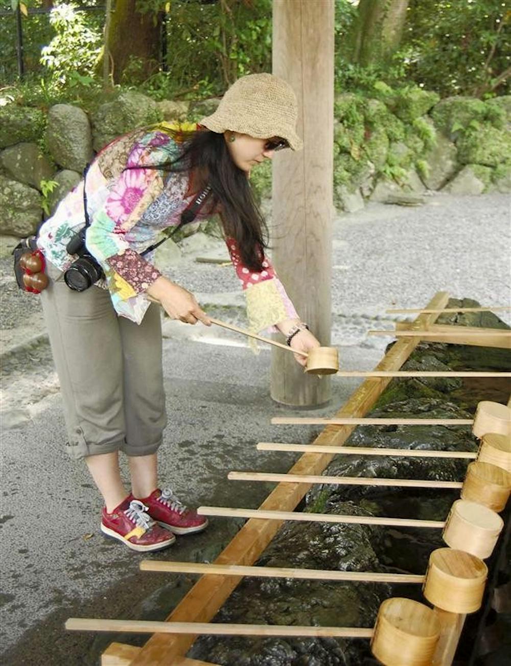 A visitor to a Shinto shrine in Osaka, Japan, washes her hands in a stone wash basin at the shrine’s entrance in preparation for prayer.