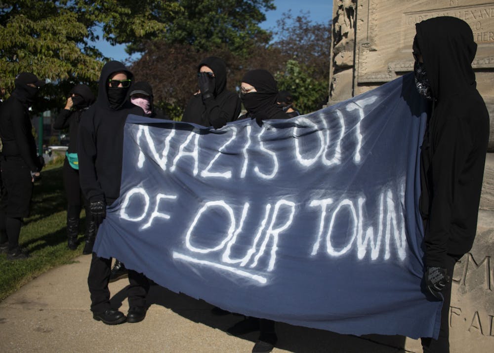 2019年8月24日，在布卢明顿的门罗县法院外，反法西斯联盟成员举着一面大横幅，上面写着“纳粹离开我们的城镇”。该组织与“无仇恨空间”组织的成员一起游行到布卢明顿社区农贸市场，抗议据称由与白人民族主义团体美国身份运动有联系的人经营的斯科纳河农场。
