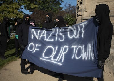 Members of antifa hold a large banner stating, “Nazis out of our town,” Aug. 24, 2019, outside the Monroe County Courthouse in Bloomington. The group, along with members of No Space for Hate, marched to the Bloomington Community Farmers’ Market to protest Schooner Creek Farm, which is allegedly run by people who have ties to the white nationalist group American Identity Movement.