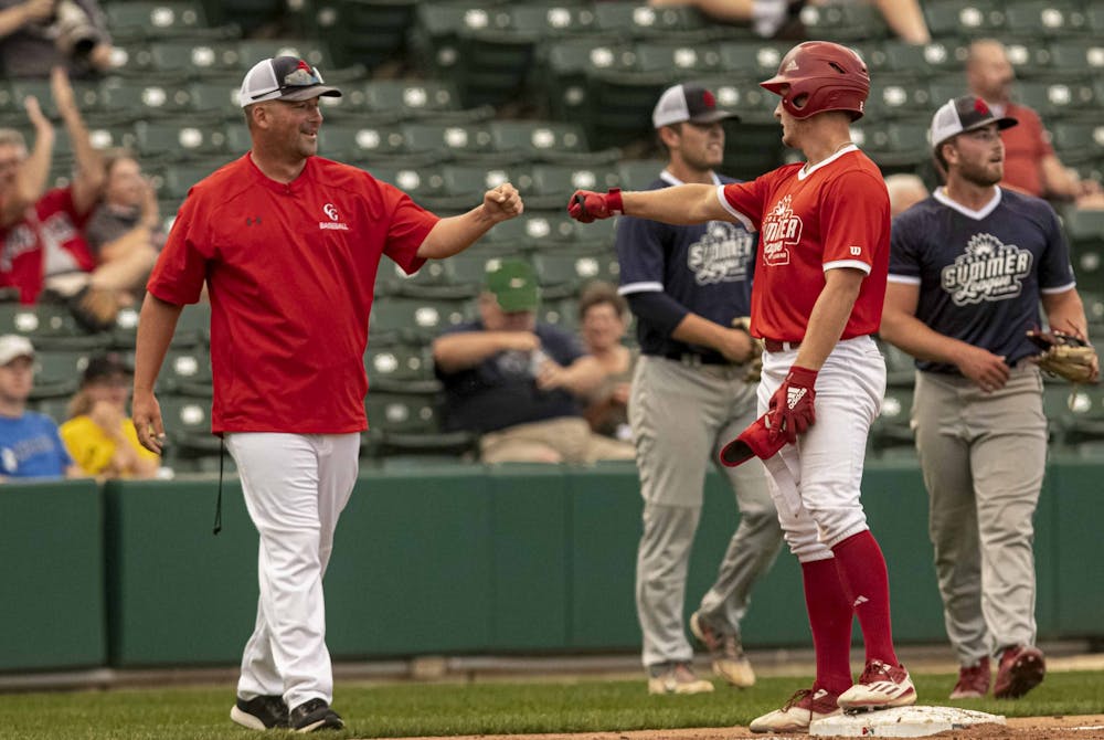 <p>Junior Cole Barr gives red team third base coach Kevin Conder a fist bump after hitting a three-run triple July 16 at Victory Field. Barr’s triple led the red team to overpower the blue team in a 4-2 victory.</p>
