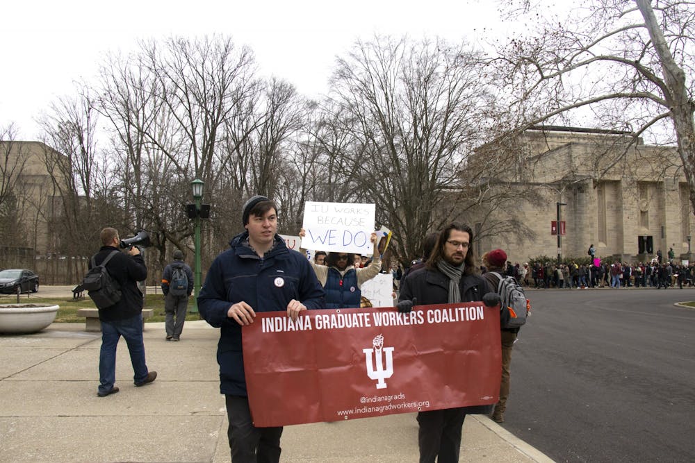 <p>Participants walk Jan. 28 to Herman B Wells Library. The Indiana Graduate Workers Coalition organized a petition to end the mandatory fee and international student fee for graduate student workers.</p>