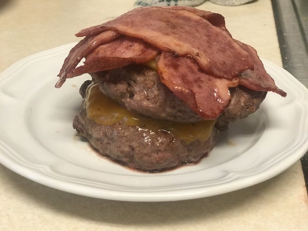 The burgers and bacon for the Burgerizza rest on a plate.