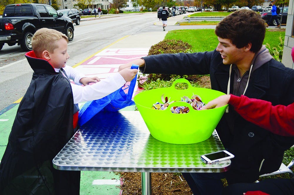 Sigma Alpha Epsilon brother Nathan Rosebrock passes out candy to Austin Matlock during Panhellenic Safe Halloween Wednesday evening.