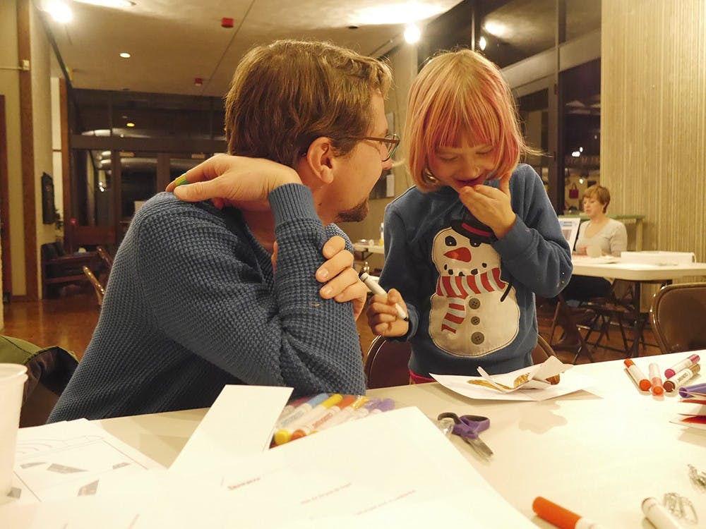 John Boshears and Charlotte Boshears make pop-up holiday cards during "Craftapalzza" on Thursday evening at the Mathers Museum. 