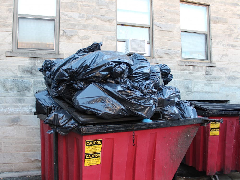 A tower of black garbage bags full of trash fills a red dumpster on Feb. 20, 2023 outside of the Wright Quad dining hall. Because roughly 10% of Bloomington’s recycling is contaminated by non-recyclables, it ends up being sent to dumpsters. 