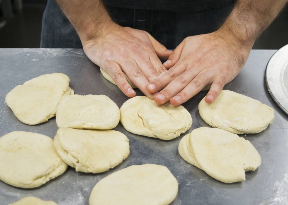 Jacob Grimsley, the shift manager, uses his hands to flatten out balls of dough. Grimlsey began working at Azzip a week before the restaurant's grand opening on Oct. 14. "It's a great place to work," he said. "Everyone is awesome."