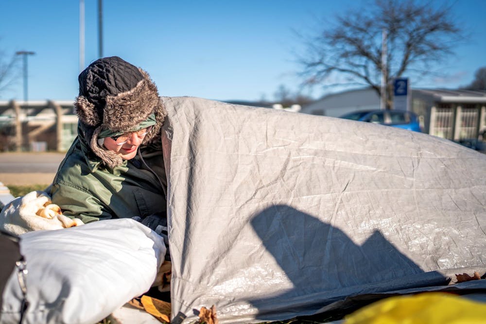 <p>A student climbs under a tarp to rest before the Indiana Men’s Basektball game versus North Carolina. Groups of students gathered across from Assembly Hall on Nov. 30, 2022.</p>