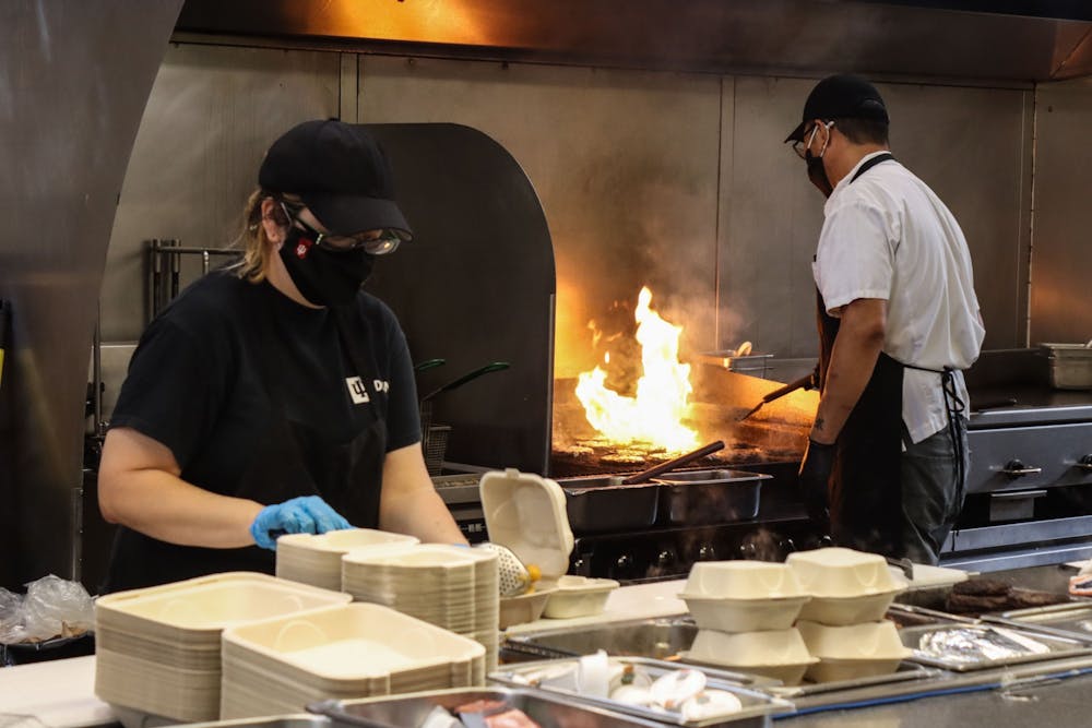 IU Dining员工Cassi Abts将食物放入2021年8月29日，在Wright四边餐厅。等待食物可以在校园内的一些IU用餐地点向上伸展三个小时。