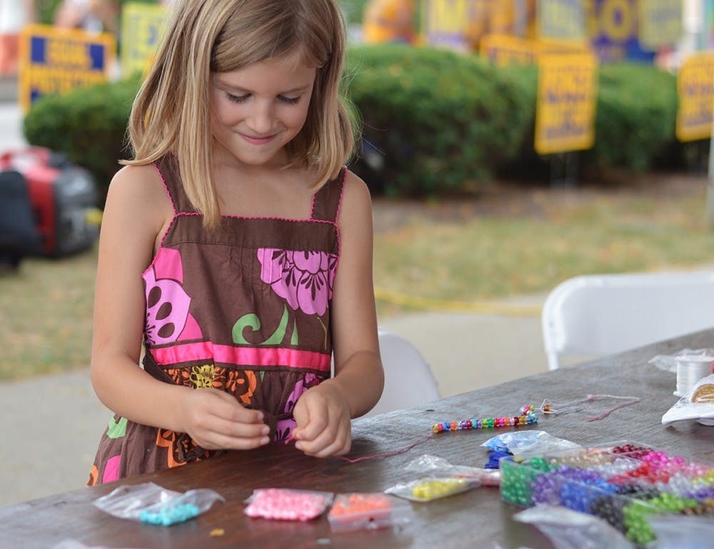 Therese Strosberg, 7, makes a beaded necklace as part of the festivities of last year's Summerfest Bloomington Pride event in downtown Bloomington.