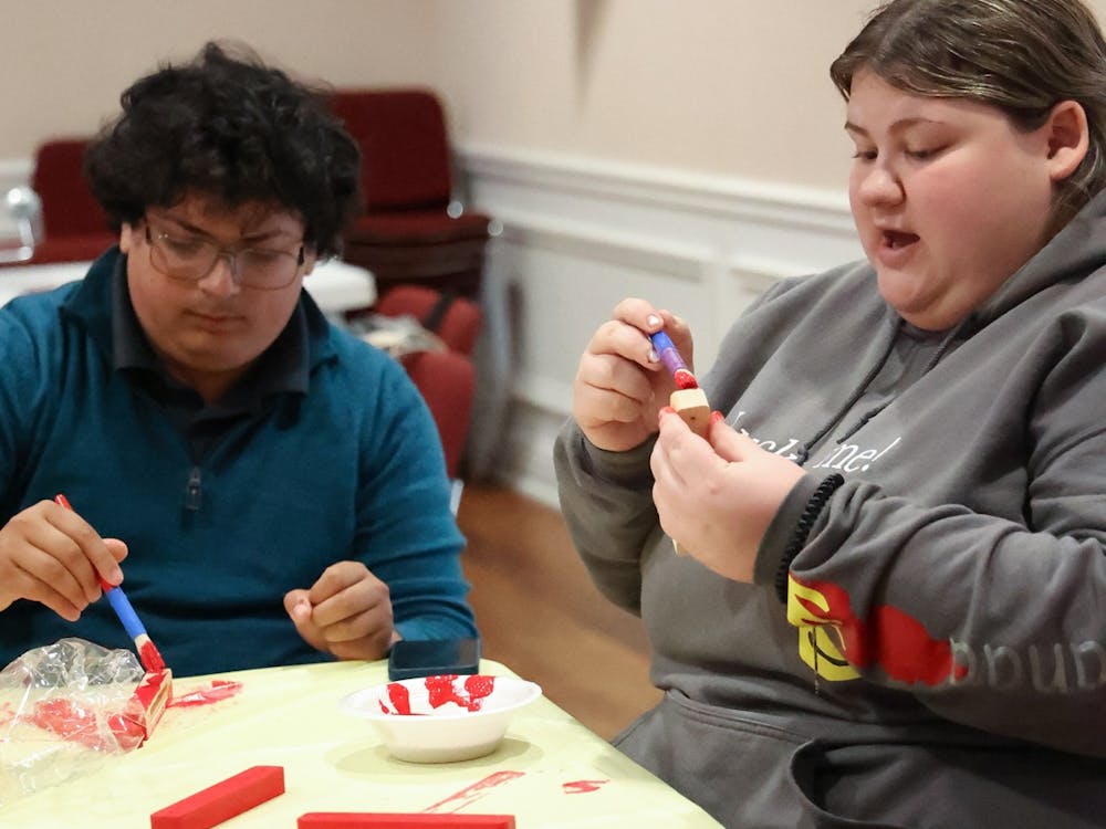 Jared Cohen and Sophie Shafran paint mezuzahs red at an antisemitism task force meeting﻿  Oct. 11. The mezuzahs they are painting are to be passed out to students who want them; either for t﻿raditional use or to stand in solidarity with the Jewish community on campus.