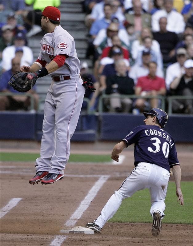 Milwaukee Brewers' Craig Counsell (30) runs back to first as Cincinnati Reds first baseman Joey Votto can't handle a throw on a ball hit to right field by Jason Kendall during the fourth inning of a baseball game Wednesday in Milwaukee. Counsell advanced to third on the throwing error.