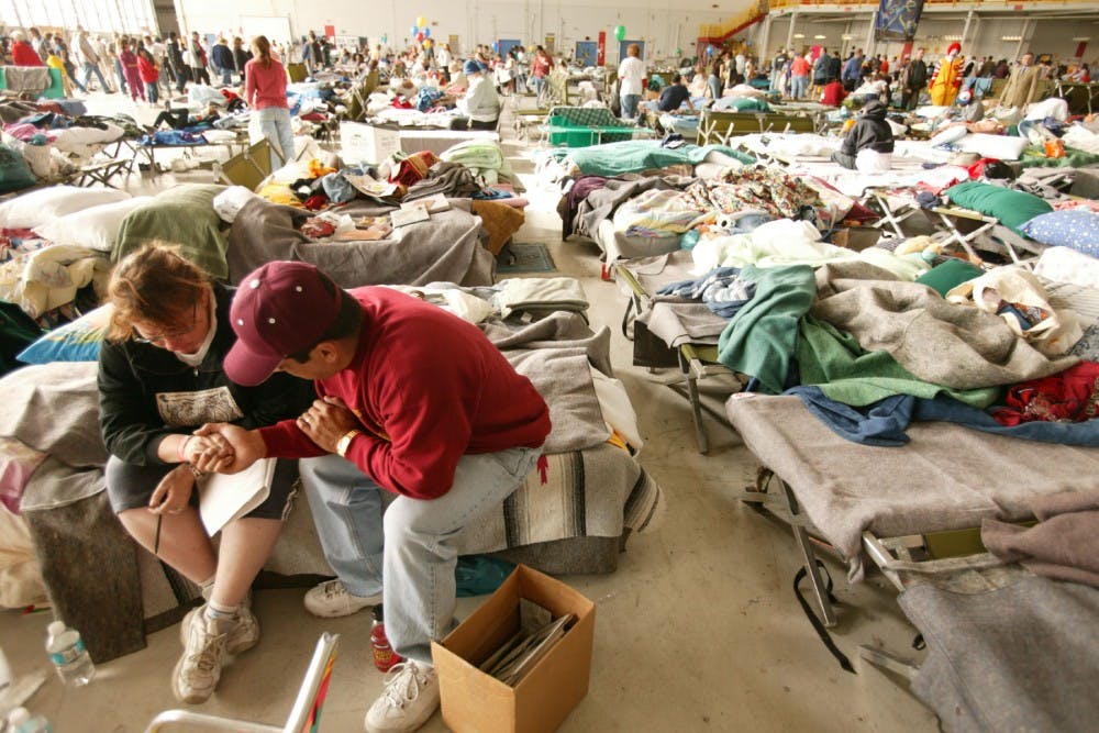 10-31-03 San Bernardino, CaliforniaReverend Misael prays with shelteree Jeri Wilde in evacuation shelter  at Norton Air Force Base.  Hanger  3 housed over 3000 evacuees following the fires in Southern California.  Photo by Andrea Booher/FEMANo Payment/Mandatory credit