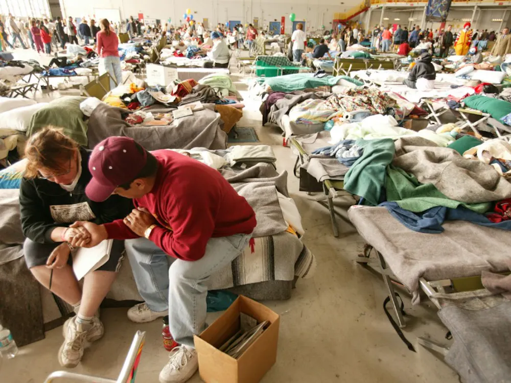 10-31-03 San Bernardino, California
Reverend Misael prays with shelteree Jeri Wilde in evacuation shelter at Norton Air Force Base. Hanger 3 housed over 3000 evacuees following the fires in Southern California.
Photo by Andrea Booher/FEMA
No Payment/Mandatory credit