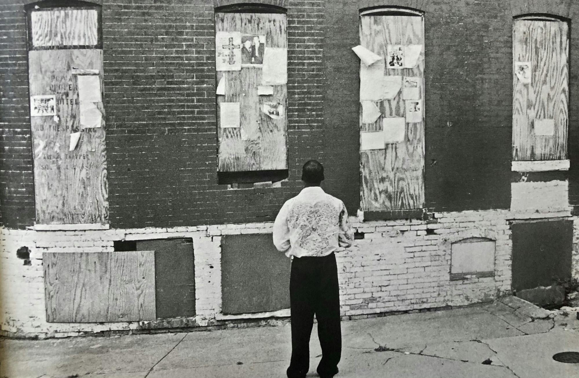 COURTESY OF ELIZABETH BARBUSH
Gresham stands before boarded-up homes that EBDI promised to renovate.