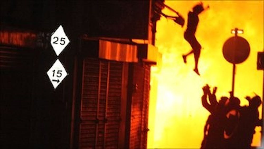 A woman leaps from a burning building in London last night. Courtesy of the BBC