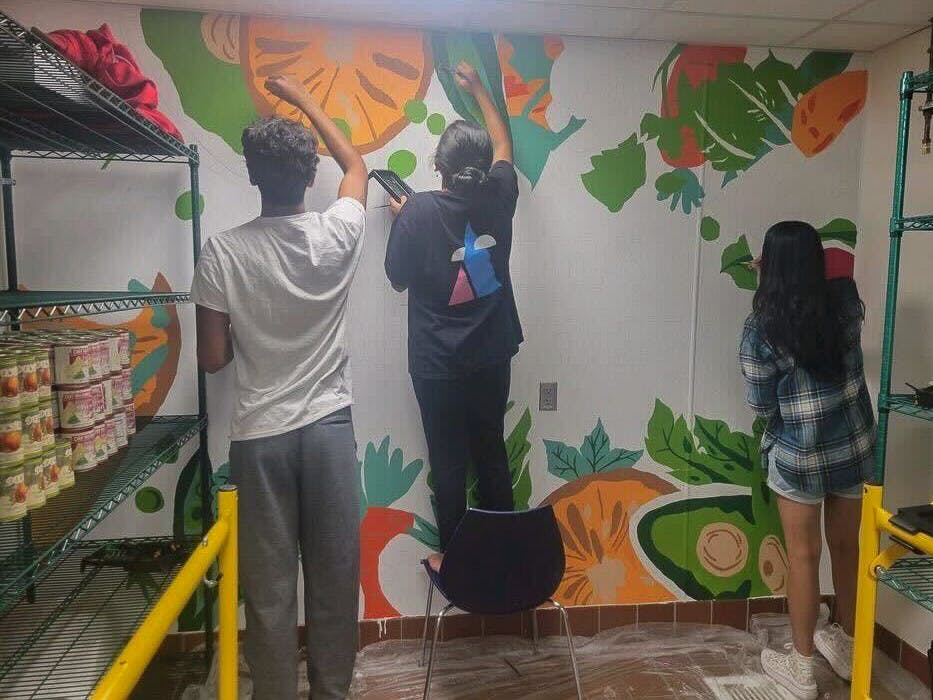 COURTESY OF ANANYA MUKUNDAN&nbsp;
bARTimore members paint a a vegetable-themed illustration in the Hopkins food pantry.
