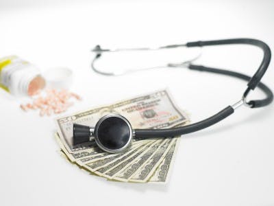 Stethescope with pills and money over white background