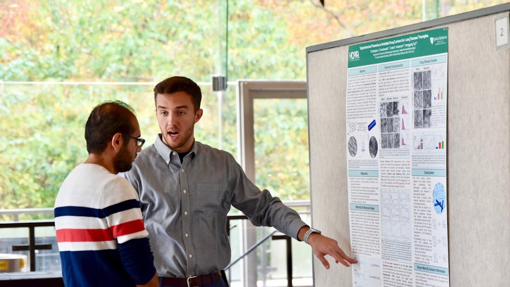 COURTESY OF THE INSTITUTE FOR NANOBIOTECHNOLOGY
Christopher Domalewski, who won Fan Favorite, explains his project to Ahmed Shabana, a postdoctoral fellow. 