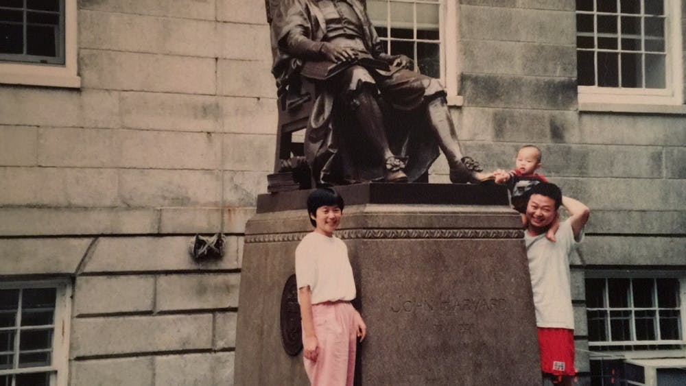 COURTESY OF ROLLIN HU
Hu, pictured top right, visits John Harvard’s statue with his parents.