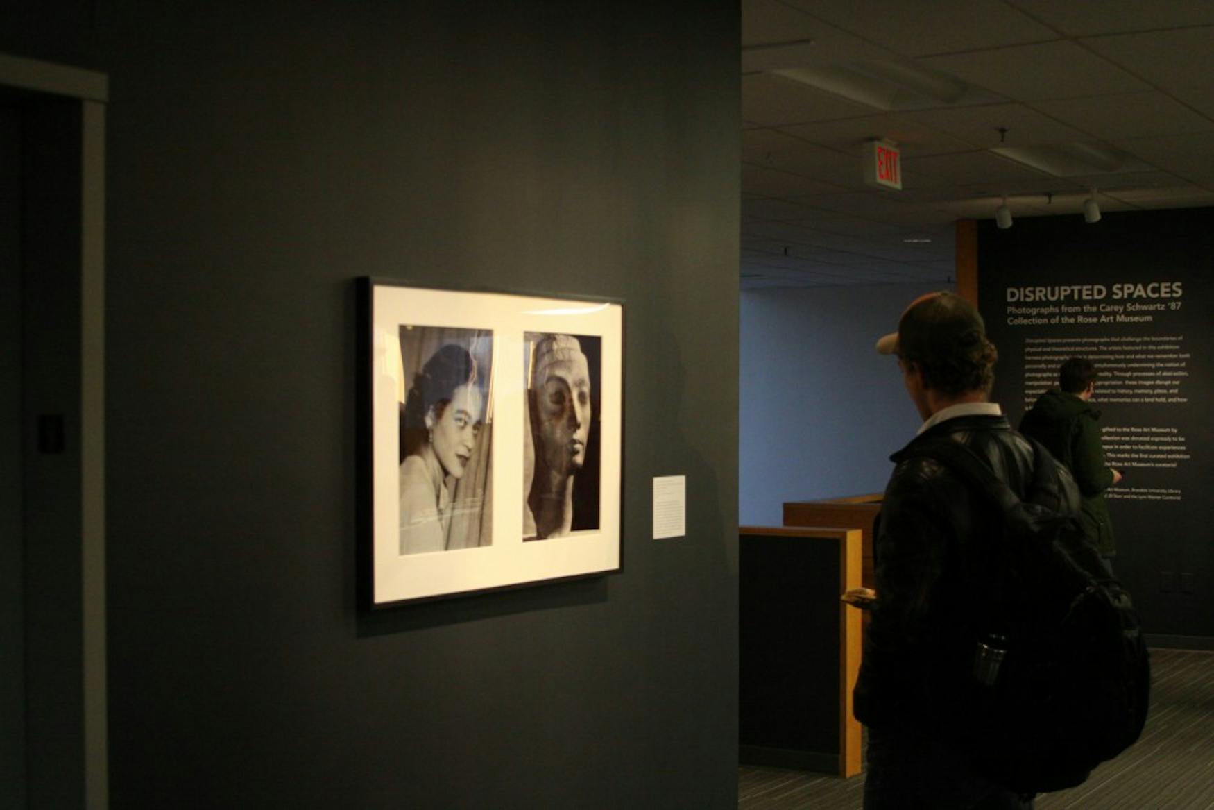 ABOUT FACE: A student looks on at photographs of two women’s faces. The series implies a narrative between the two black and white photos.