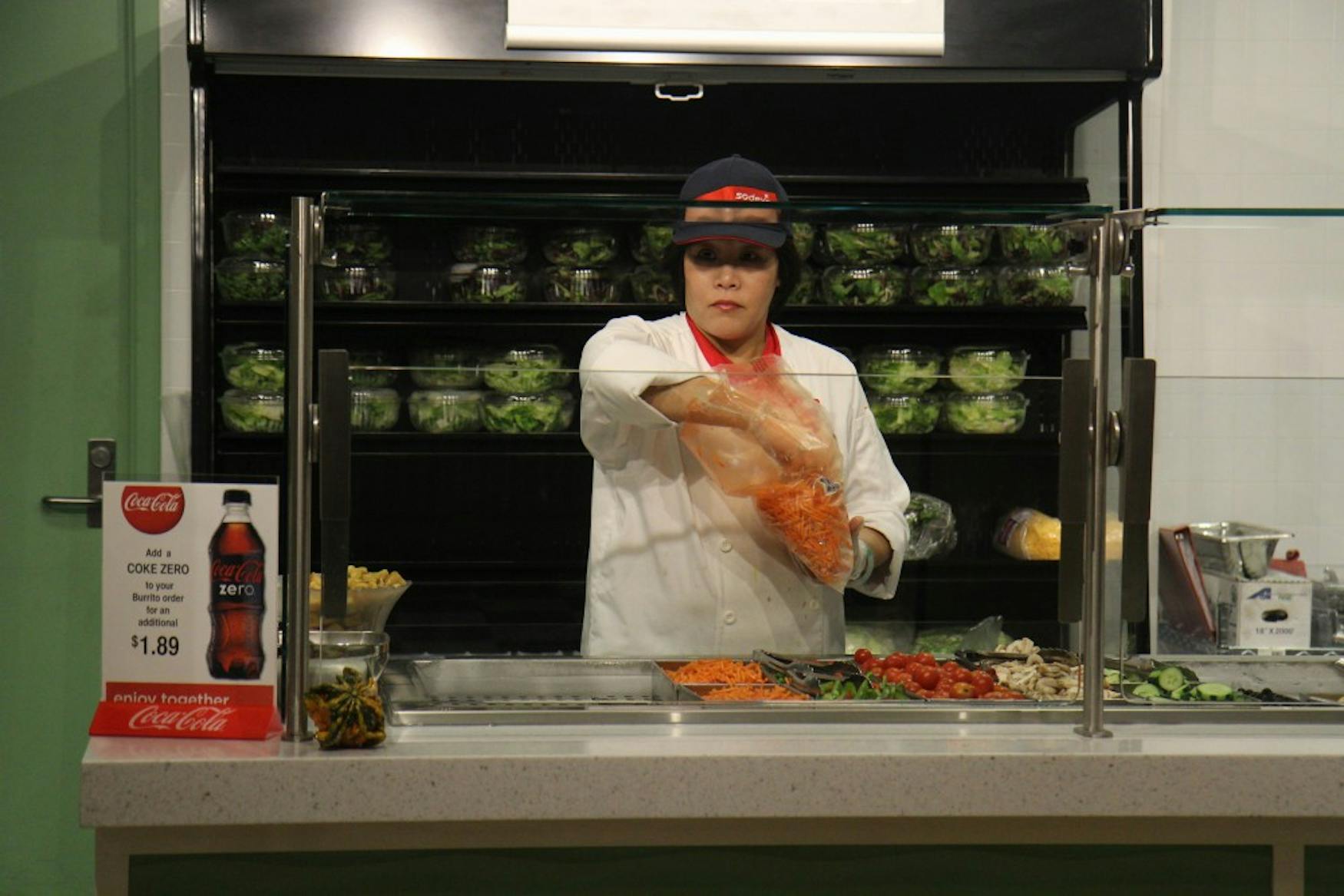 Lucia, who works at the salad station in the Usdan food court, refills the station with carrots.