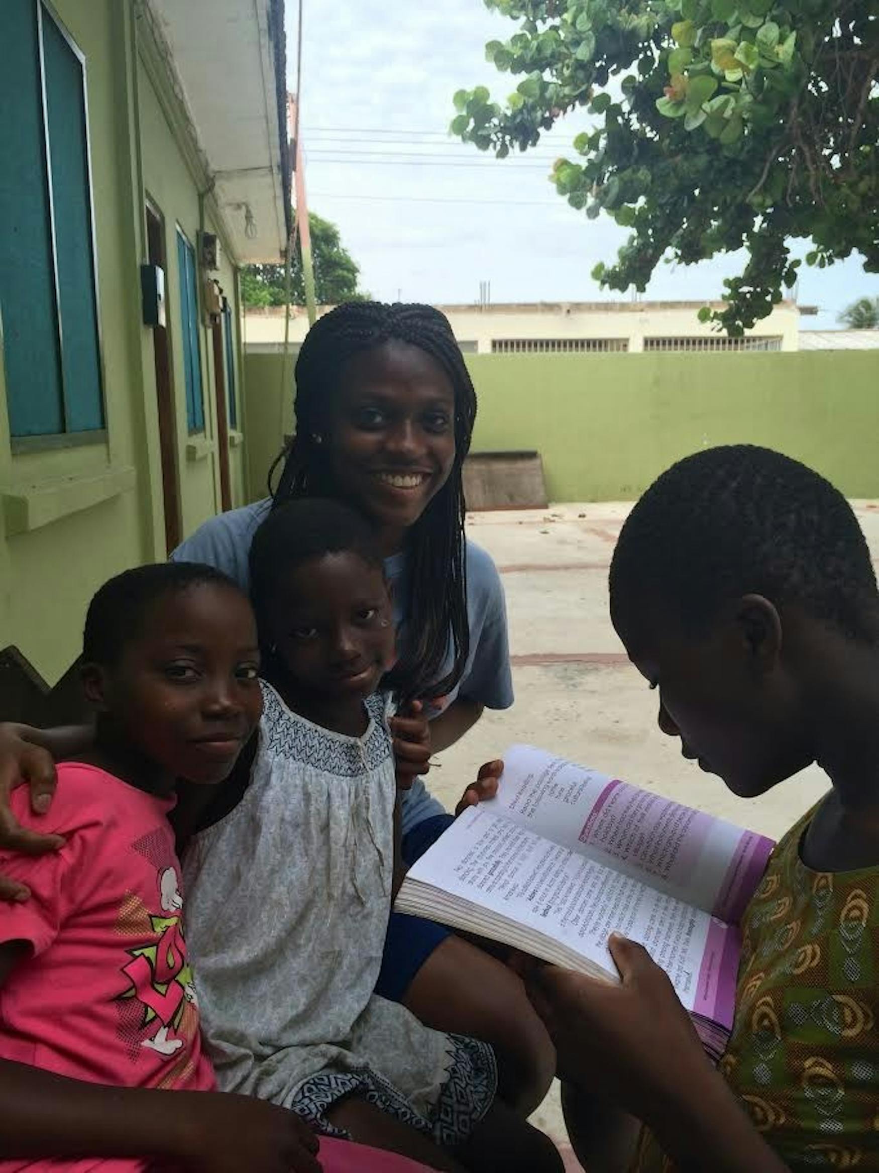 HELPING HANDS: Ngobitak Ndiwane '16 (center) helps students with their homework on the compound where she spent the summer in Atorkor, Ghana.