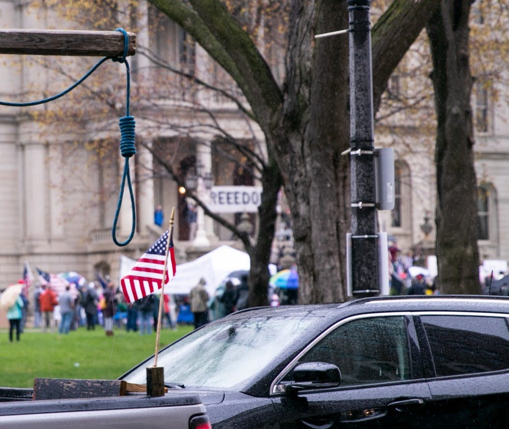A truck hanging a noose in the trunk drives past the rally at the Capitol April 30, 2020 in Lansing.