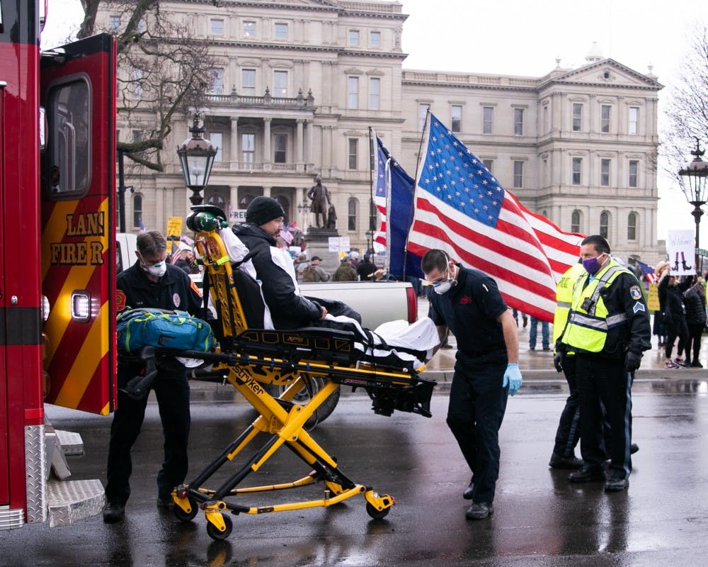 A man on a stretcher is put into an ambulance at the rally at the Capitol April 30, 2020 in Lansing.