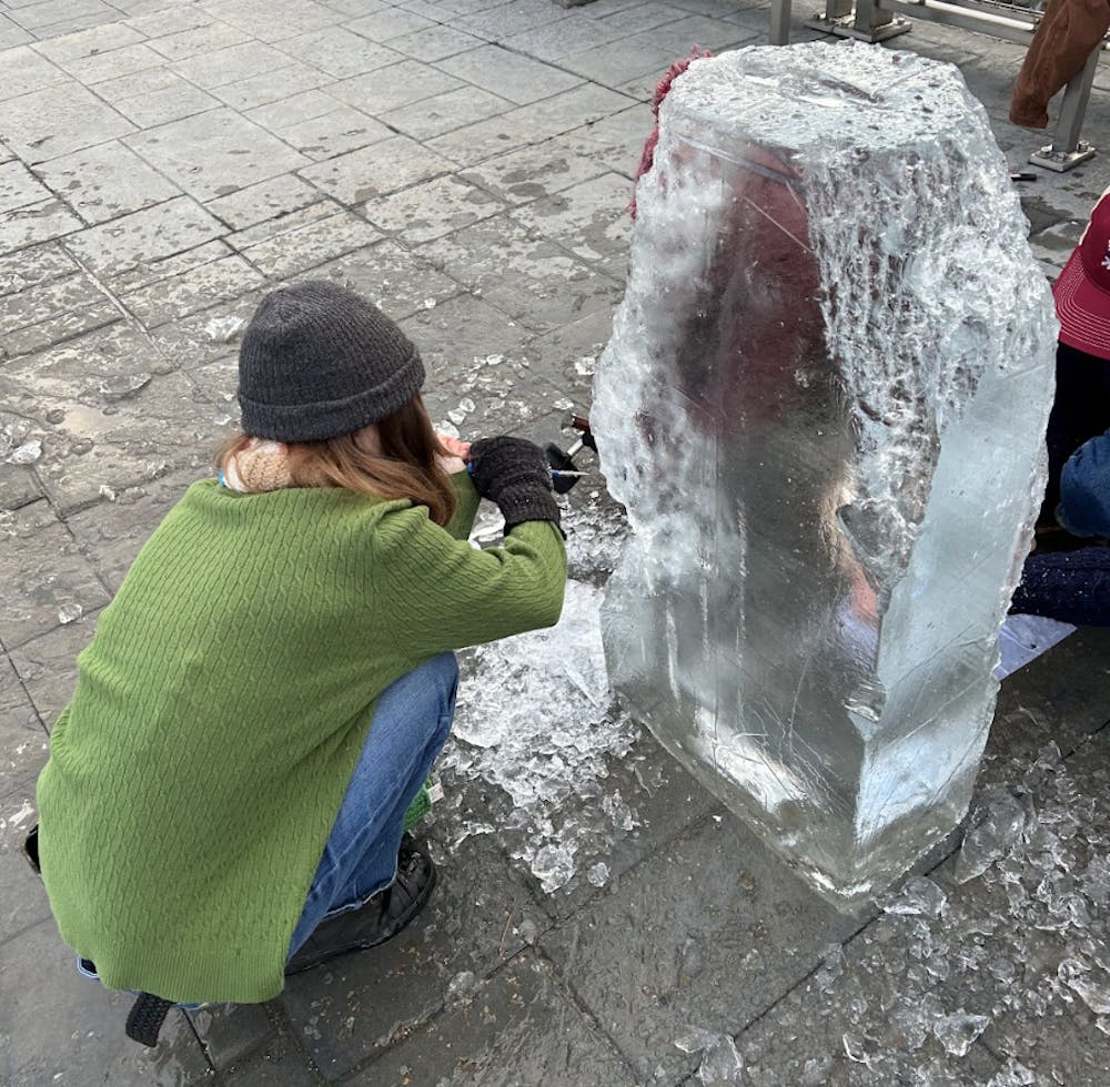 Participants in the ice sculpture competition on Friday of carnival weekend carve a fish design out of the ice block.