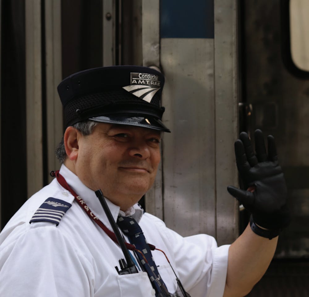 An Amtrak conductor waves as the train boards.