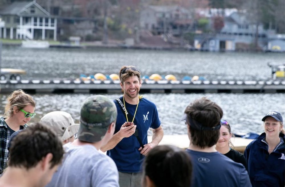 Rich Connell, the head coach of Middlebury Crew, stands alongside student-athletes on a 2019 spring break trip to Lake Lure, North Carolina. COURTESY OF SOPH CHARRON