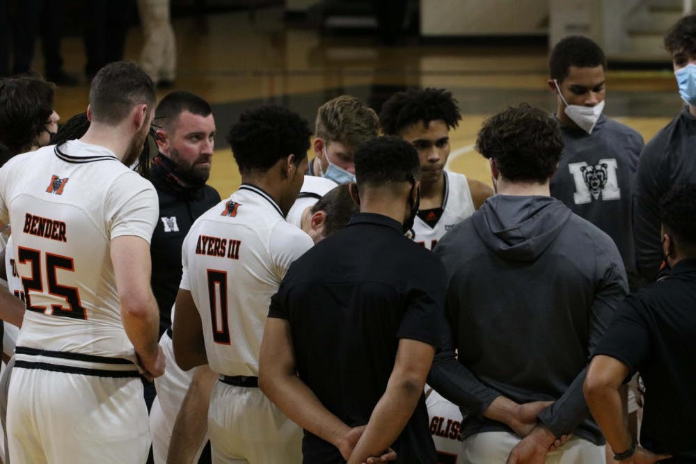 The men's basketball team gathers in a huddle in an earlier game this season.