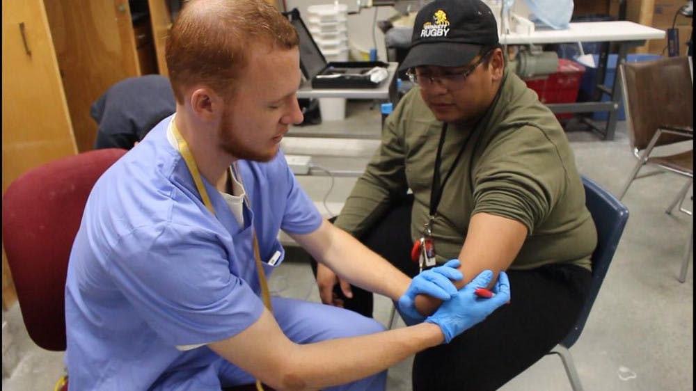 Andrew Roy takes measurements of David Torres’ arm to fit for the prosthetic.