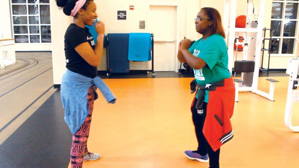 Blossom Onunekwu (left) and Keyana Boone (right) get in position to perform squats in the UC gym. 