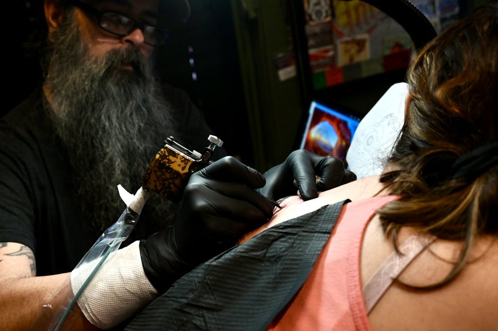 <p>Tattoo artist and Redemption Tattoo co-owner Chris Dorrough tattoos a client in his studio. The shop gives a 10% discount to college students and brings their hourly rate down from $150 to $130.  </p>