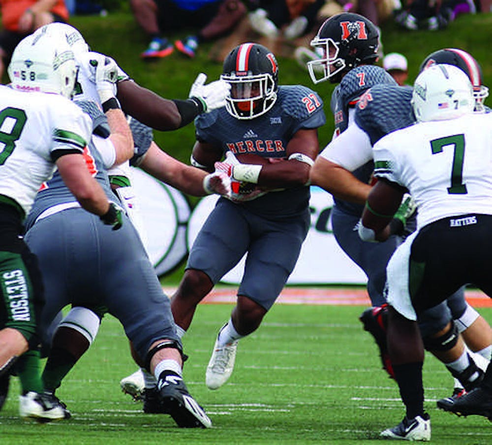 Mercer's Alex Lakes (27), middle, weaves through football players in their game against Stetson.