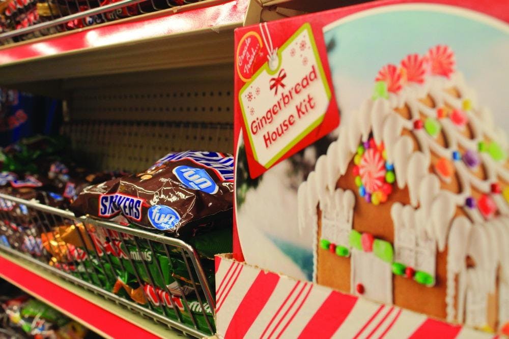 Christmas gingerbread house set on shelf directly by Halloween candy.