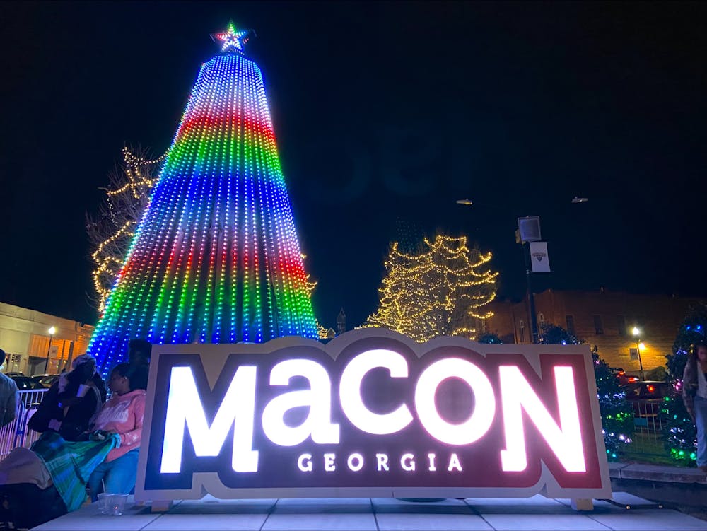 An led-light Christmas tree stands behind a sign welcoming visitors to Macon at the intersection of Poplar Street and Second Street.