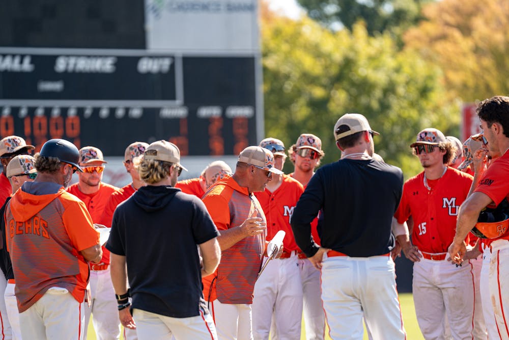 The baseball team listens in on Coach Craig Gibson during a spring practice session.