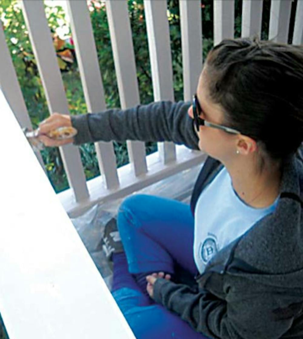 Sophomore Indie Coombs paints a front-porch during Facade Squad, a recent service project led by the Mercer Service Scholars. SPECIAL PHOTO.