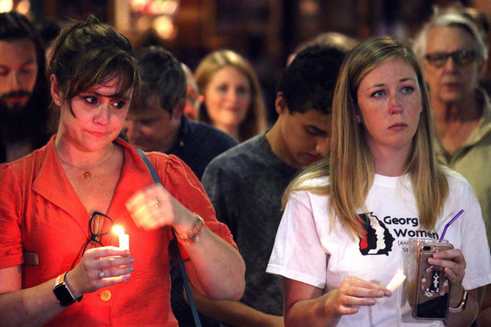 Jenny Wright (left) and Courtney Britt (right) stand for a moment of silent reflection during Lights for Liberty, a candlelit vigil protesting the conditions of migrant detention centers.