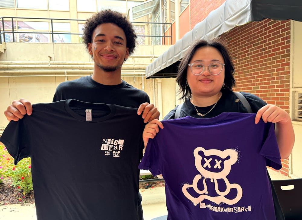 Kaitlyn Lee '27 and Sebastian Blanco '26 pose with the 2024 Be a Good NeighBear T-shirt design. Volunteers receive their free shirts after they finish their service shift.